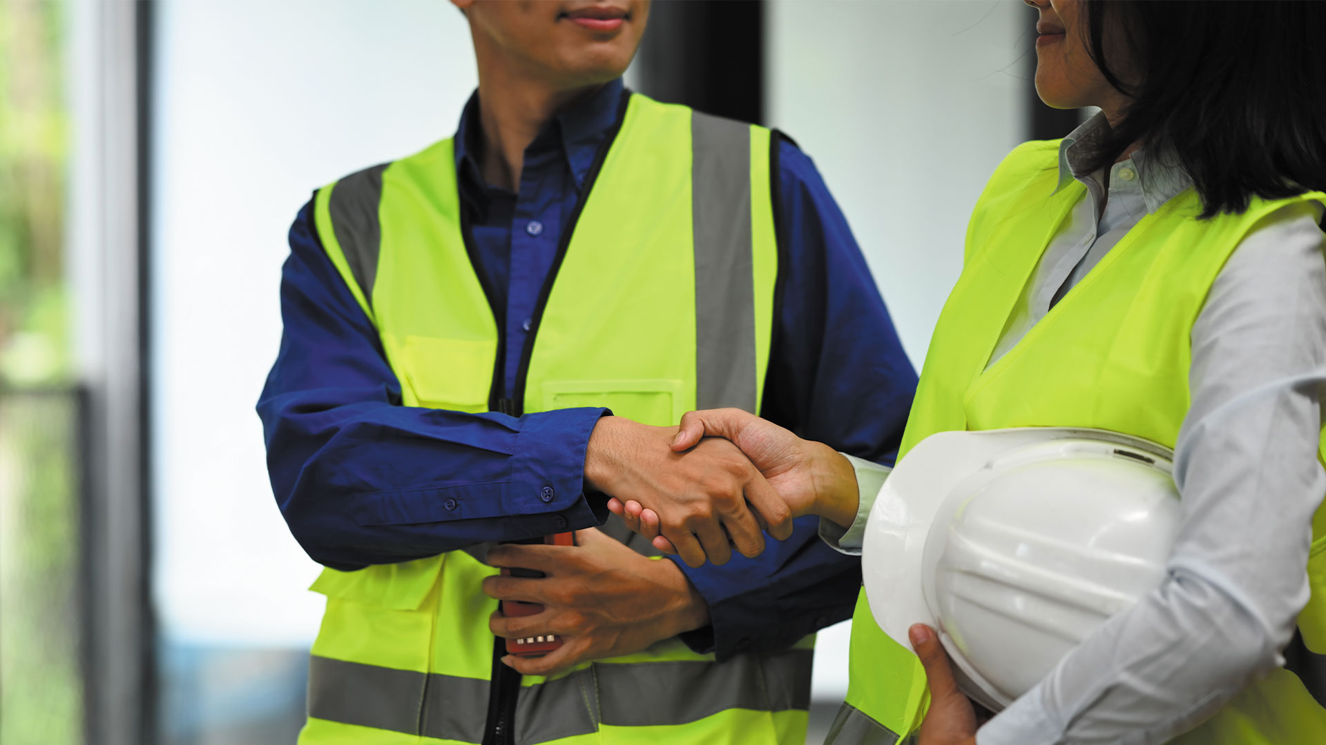 People shaking hands wearing high vis vests